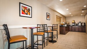 A dining area with two tables and chairs, a kitchen with a coffee station, and framed artwork on the wall. - Best Western Heritage Inn (Vacaville)