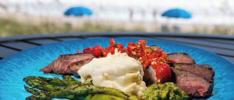 A blue plate with steak, asparagus, mashed potatoes, and a tomato-based sauce.