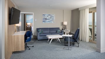 Een hotelkamer met een bureau, een bank, een stoel, een televisie, een lamp en een schilderij aan de muur.