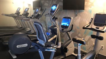 A gym with various exercise equipment including treadmills, elliptical machines, and a stationary bike.
