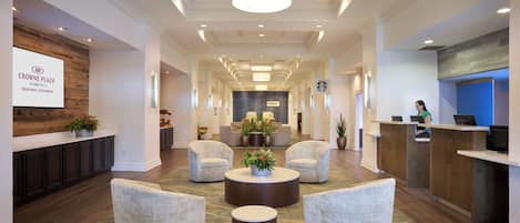 A hotel lobby with a reception desk, seating area, and a large screen displaying the hotel name.