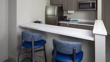 Una cocina compacta equipada con refrigerador, microondas y taburetes de bar.