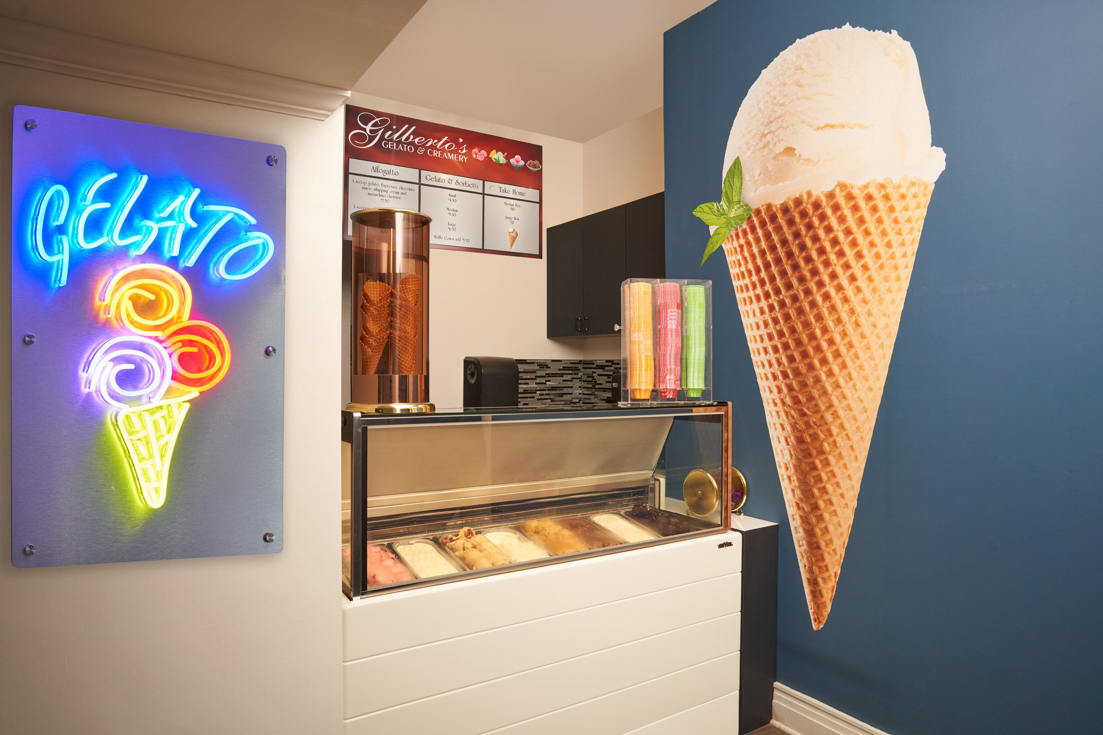 Una heladería con un letrero de neón, un menú y una vitrina con diferentes sabores de helado.