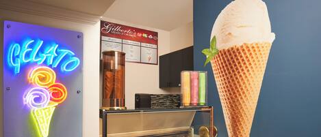 An ice cream parlor with a neon sign, a menu board, and a display case with various ice cream flavors.