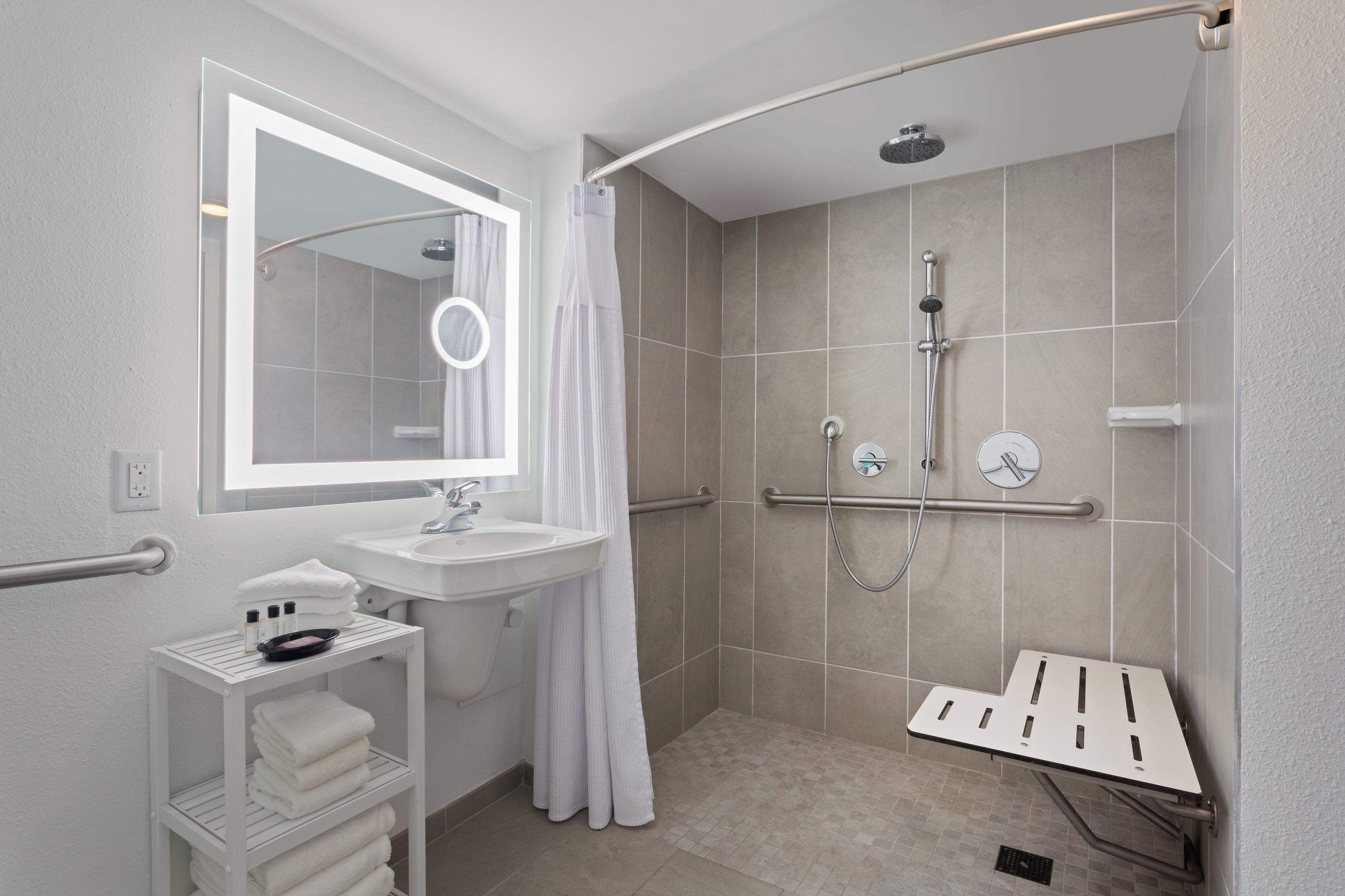 A modern bathroom with a shower, a sink, a mirror, and a towel rack.