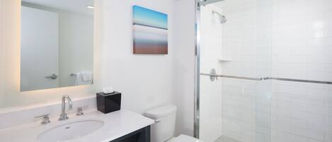 Une salle de bain moderne avec un grand miroir, un lavabo, des toilettes et une douche à parois de verre.