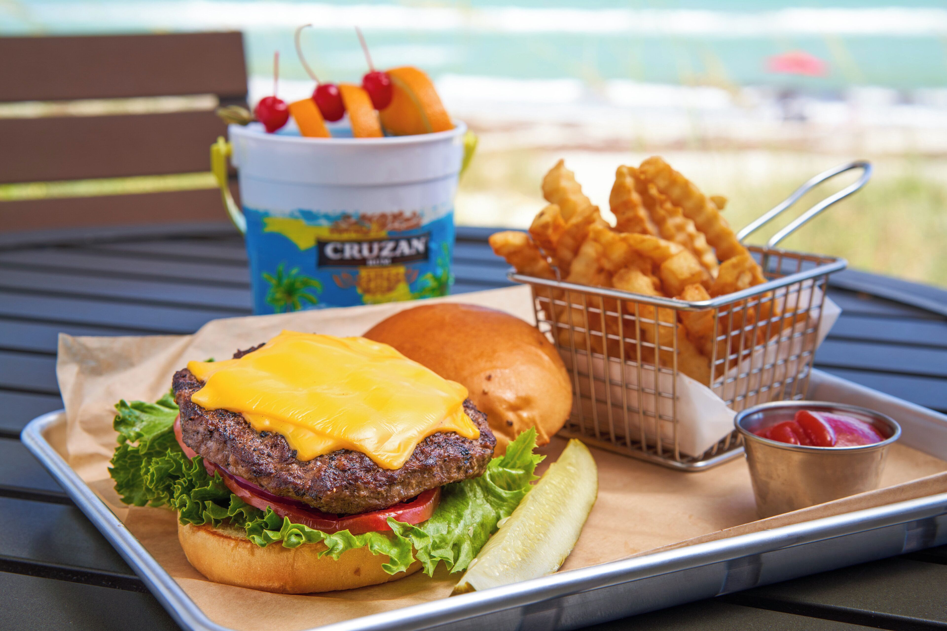 A meal consisting of a burger with cheese, fries, and a side of ketchup.