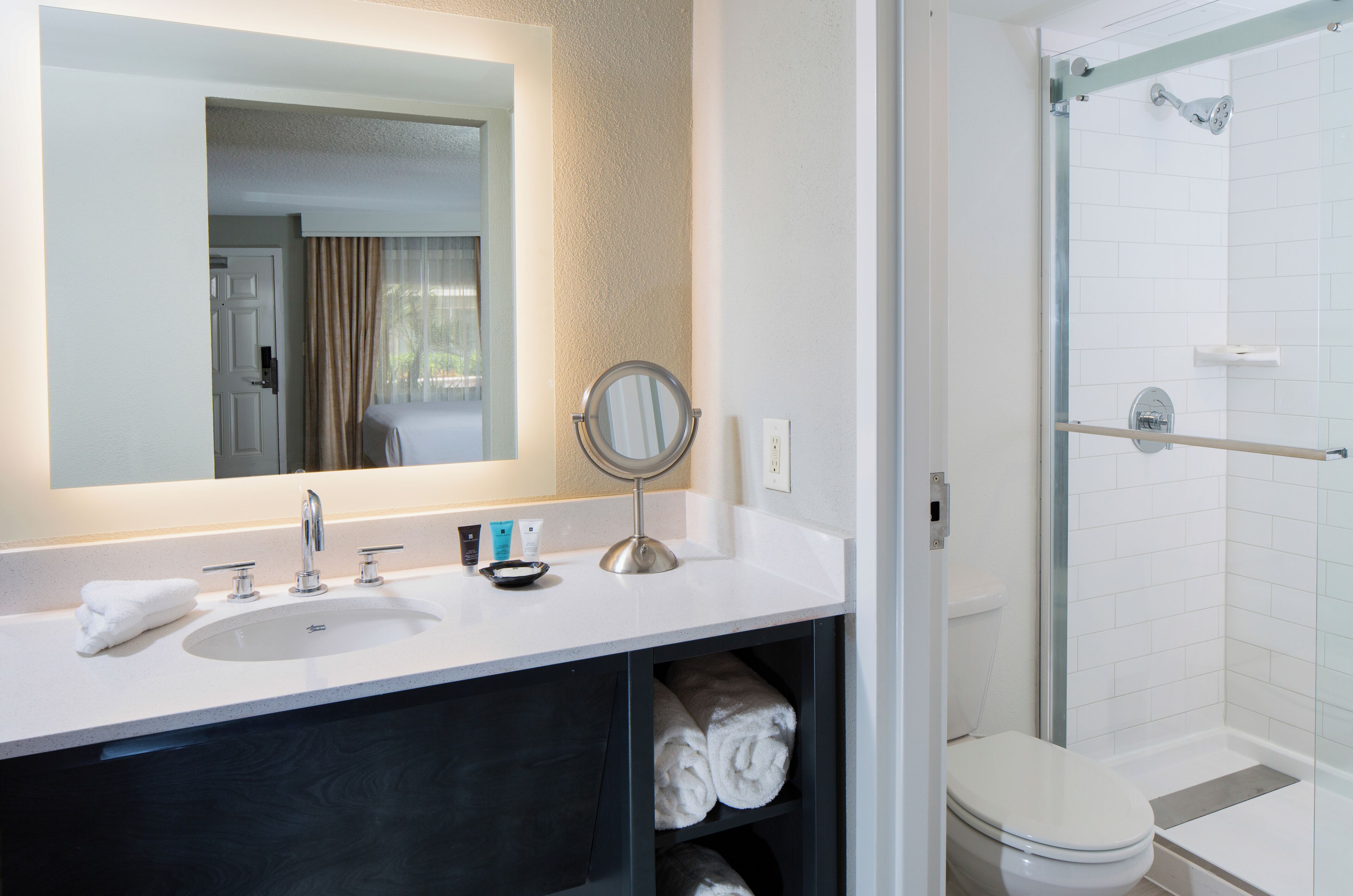 A bathroom with a white sink, mirror, and toilet, and a glass-enclosed shower area.