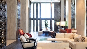 A spacious lobby with a modern design, featuring a seating area with sofas and chairs, a coffee table, and a decorative plant. - W South Beach (Miami Beach)