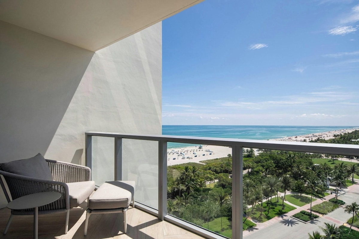 A balcony with a view of a beach and palm trees.