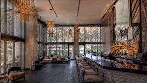 A spacious bar area with a long counter, seating along the bar, and large windows offering views of the outdoors. - W South Beach (Miami Beach)