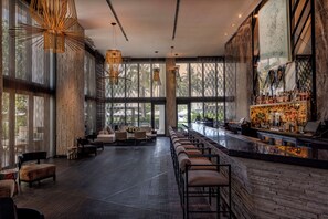A spacious bar area with a long counter, seating along the bar, and large windows offering views of the outdoors. - W South Beach (Miami Beach)