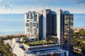 A high-rise hotel with multiple floors, balconies, and a view of the beach.