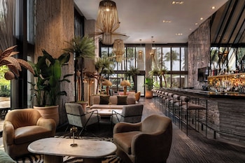A modern hotel room with a large bed, a desk, and a TV. The room has large windows with a view of the beach and ocean. at W South Beach