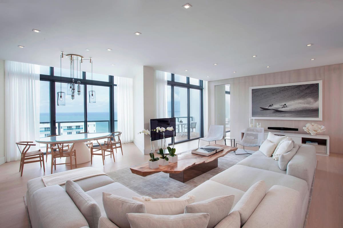 A modern living room with a large window, a wooden coffee table, a sofa, and a television.