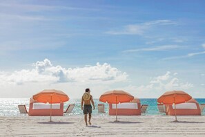 A beach with umbrellas and lounge chairs.