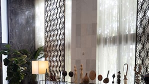 A modern interior with a marble wall, a glass display case with decorative items, and a seating area with floral ottomans. - W South Beach (Miami Beach)