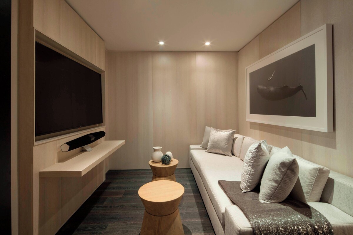 A modern living room with a flat-screen TV, a wooden coffee table, a sofa with cushions, and a framed artwork on the wall.