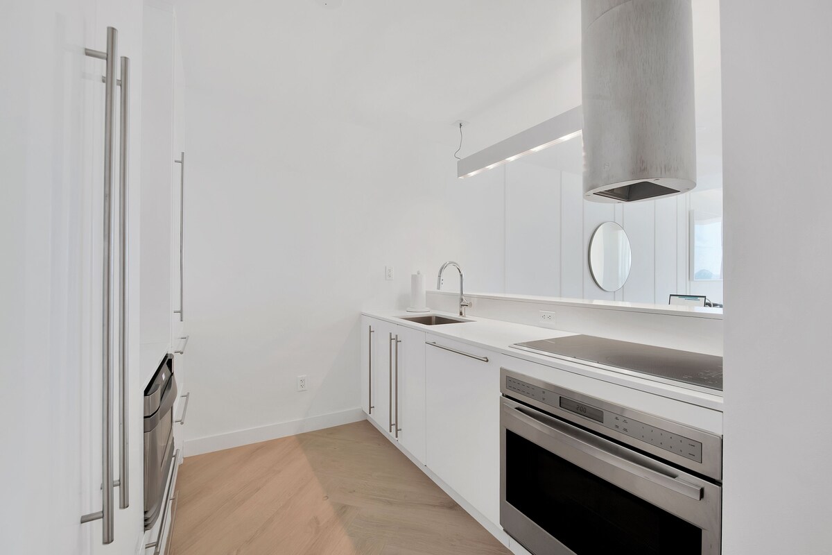 A modern kitchen with white cabinetry, a stainless steel dishwasher, and a double oven.
