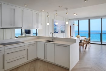 A modern living room with two sofas, a coffee table, and a bookshelf with wine bottles. at W South Beach
