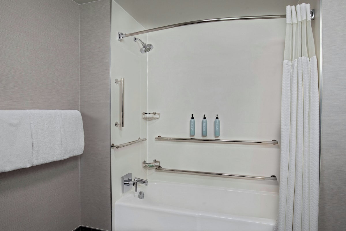 A modern bathroom with a bathtub, shower, and towel rack.