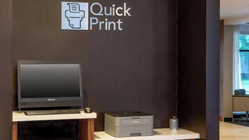 Una impresora y un ordenador portátil sobre un mostrador con un letrero que dice "Quick Print".