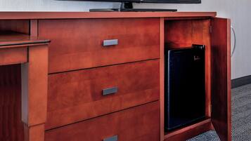 A wooden cabinet with a flat-screen TV on top and a small black refrigerator built into the cabinet.