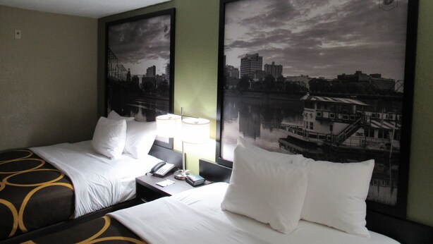 A hotel room with two beds, a nightstand with a lamp, a phone, and a cityscape view. - Super 8 by Wyndham New Cumberland (New Cumberland)