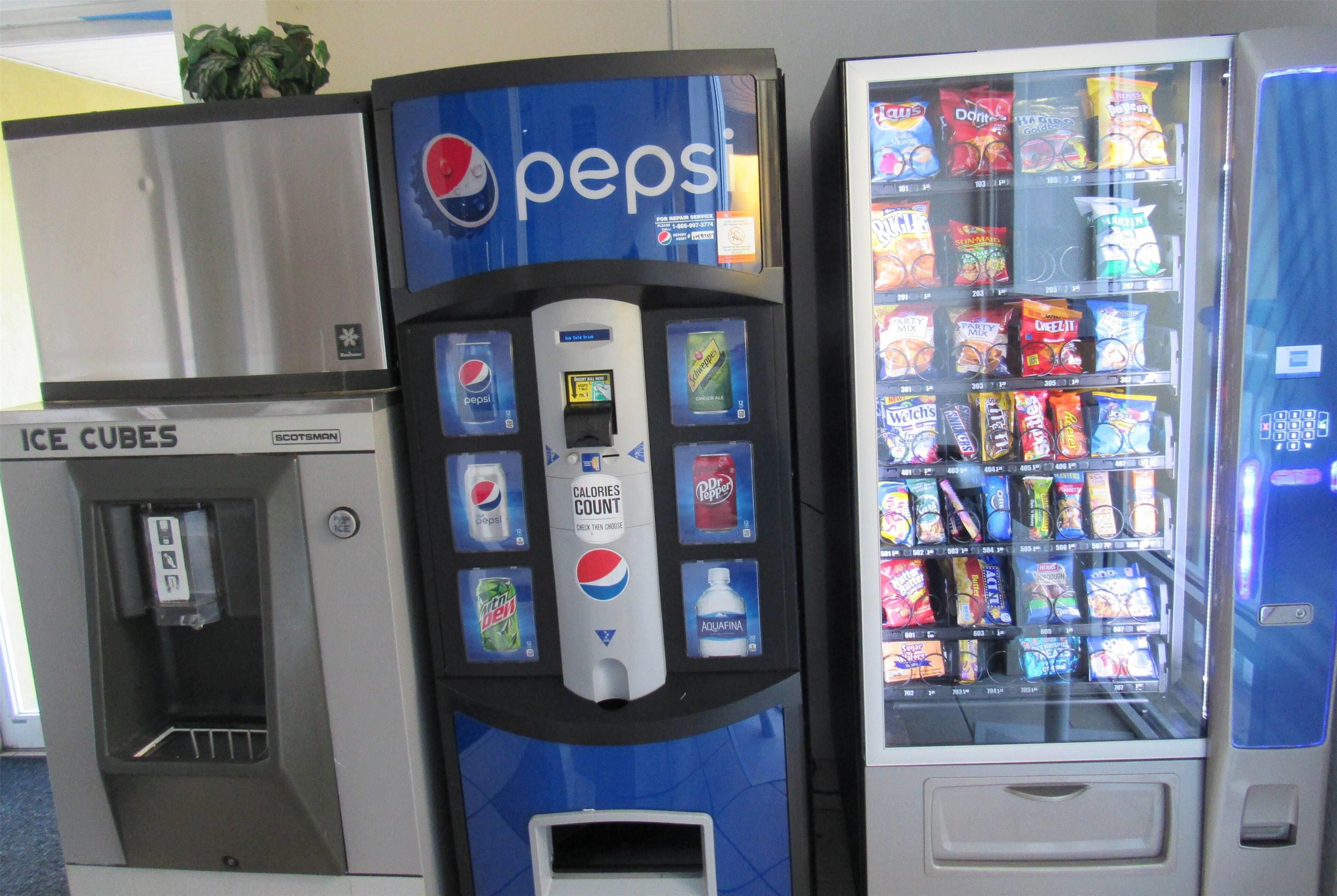 Máquina de vendas com Pepsi e dispensador de bebidas, e um freezer com cubos de gelo.