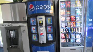 Máquina de vendas com Pepsi e dispensador de bebidas, e um freezer com cubos de gelo.