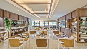 A spacious dining area with multiple tables and chairs, wooden paneling on the walls, and shelves with various items.