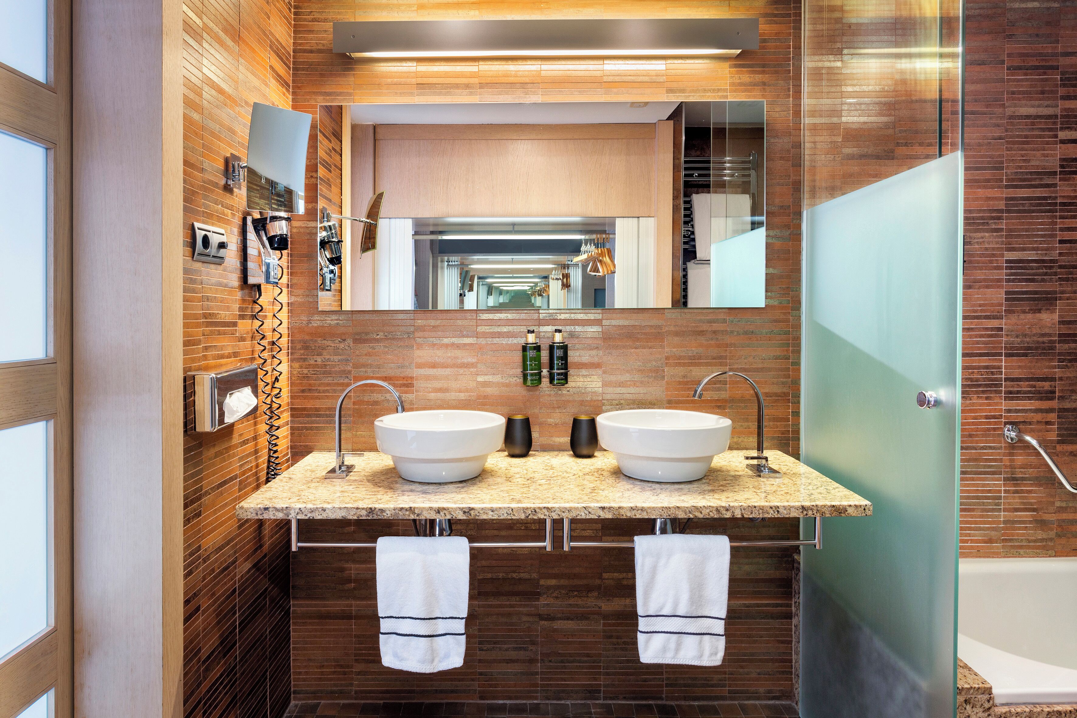 Un baño moderno con dos lavamanos, un espejo grande y cabina de ducha de vidrio.