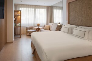 Ein Hotelzimmer mit einem großen Bett, einer Schlafcouch, einem kleinen Tisch und einem Bücherregal.