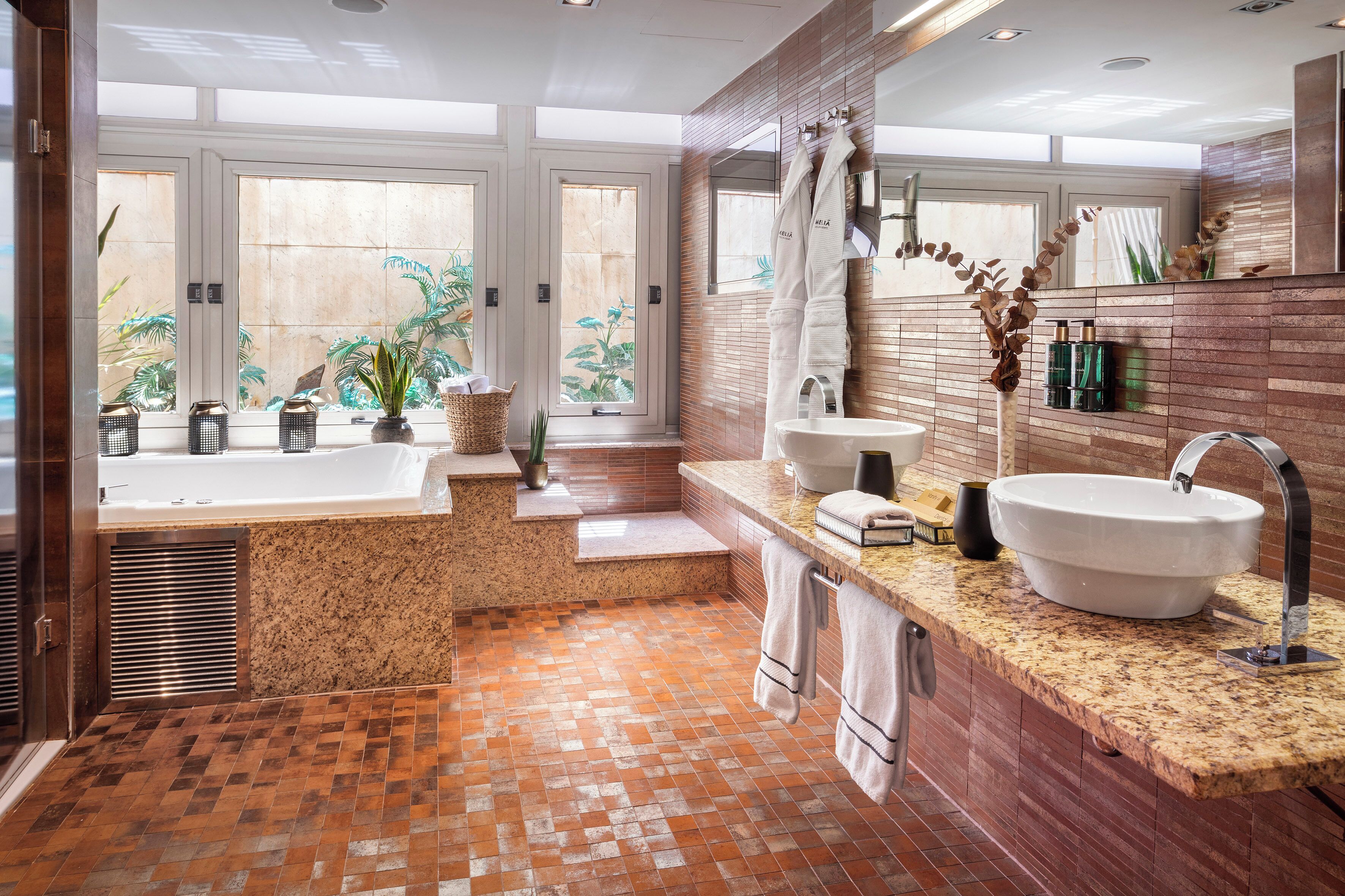 A modern bathroom with a large bathtub, two sinks, and a vanity area.