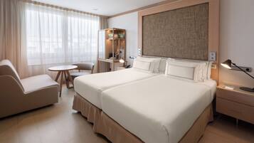 Habitación de hotel con una cama grande, un escritorio, una silla, una mesita y un sofá.