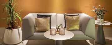 A modern seating area with a cushioned bench, two decorative vases, and a potted plant.