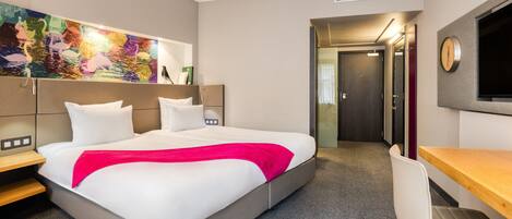 Una habitación de hotel moderna con una cama grande, un escritorio y una televisión.