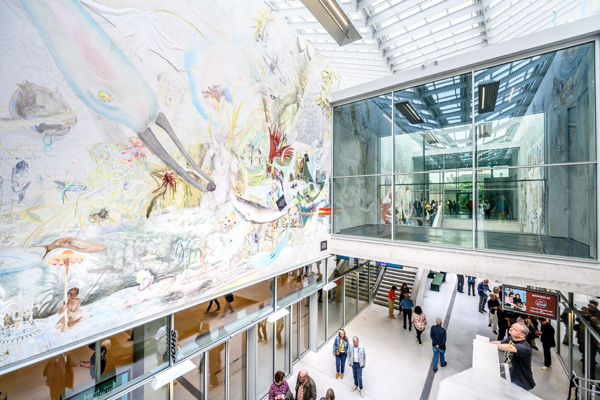 Un vaste atrium agrémenté d’une grande fresque murale, de rampes en verre et d’une conception architecturale moderne.