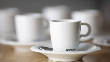 A white Nespresso cup on a saucer with a spoon, set on a table.