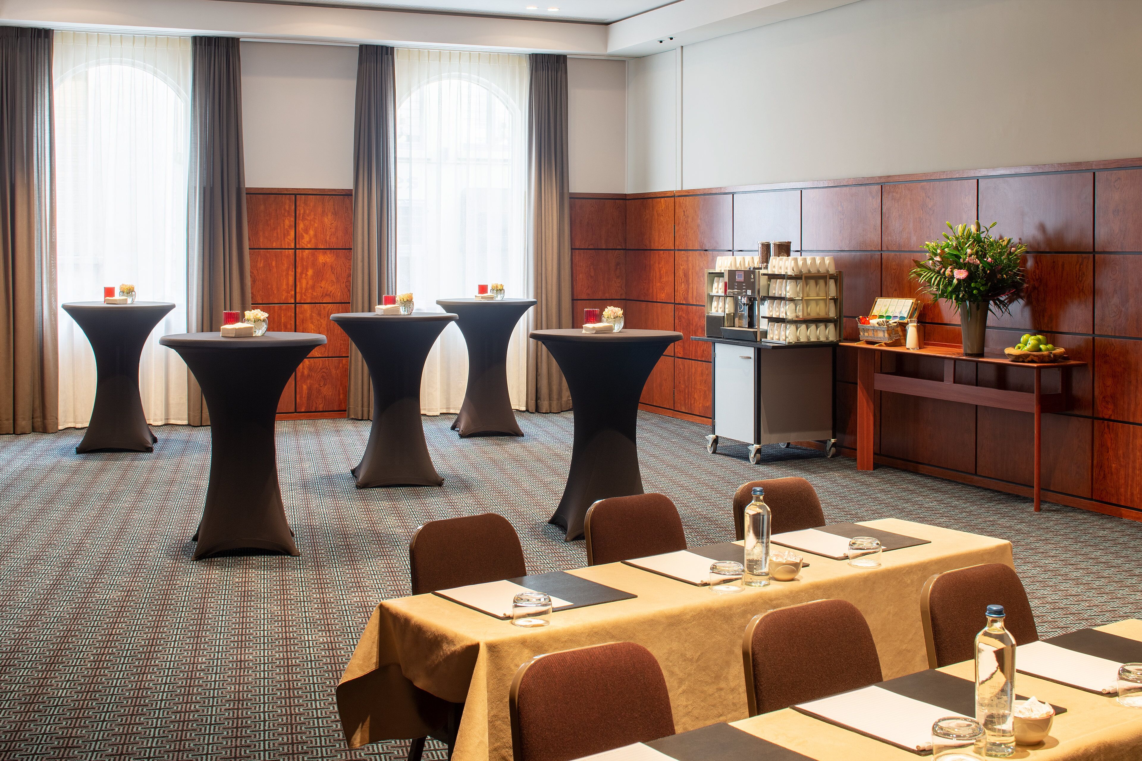 Una sala de conferencias con mesas, sillas y una estación de café.