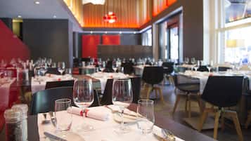Un restaurant avec de nombreuses tables dressées pour le service, comprenant des verres à vin et des couverts.