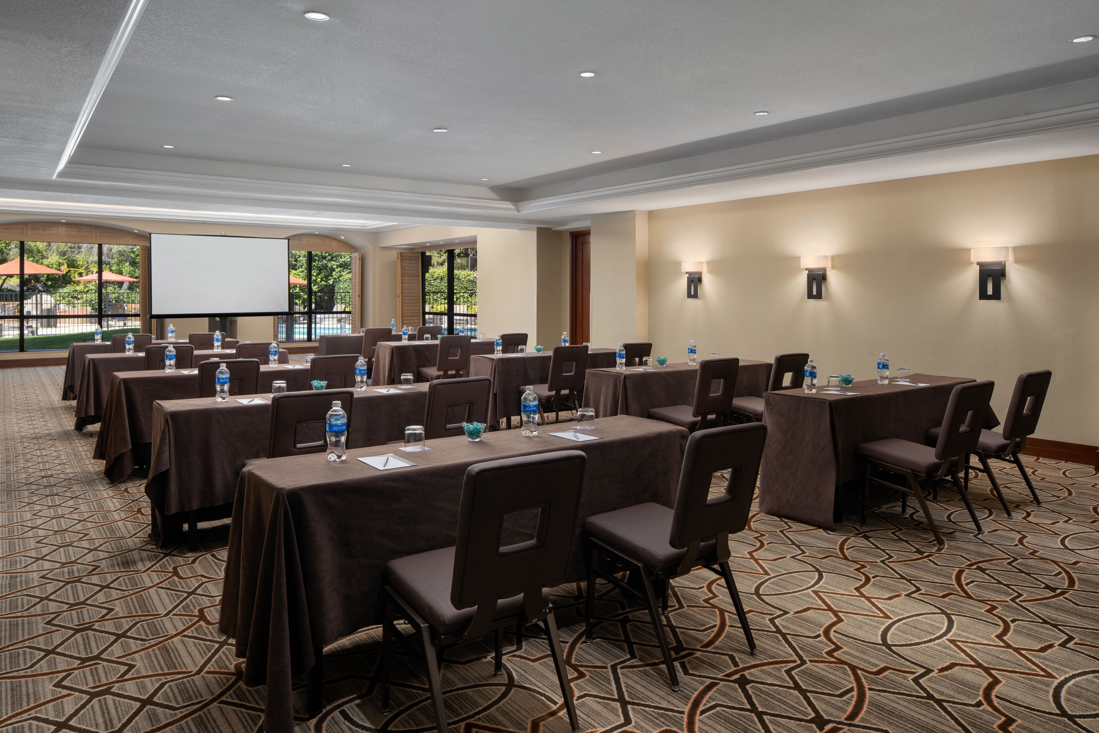 A conference room with multiple tables, chairs, and a projector screen.