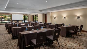 A conference room with multiple tables, chairs, and a projector screen.