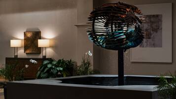 A modern lobby with a water feature, two wall-mounted lamps, and a framed artwork.