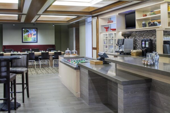 A modern bar area with a counter, seating, and a coffee machine.