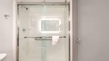 A glass-enclosed shower with a towel rack and a visible bathroom sink.