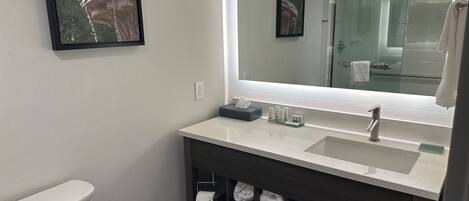 A modern bathroom with a white sink, dark vanity, and a large mirror.