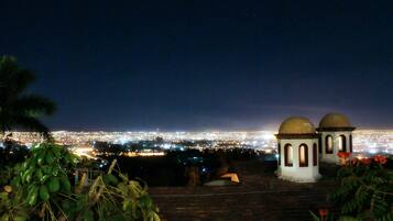 A night view of a cityscape with two domed structures and a distant city illuminated by lights.