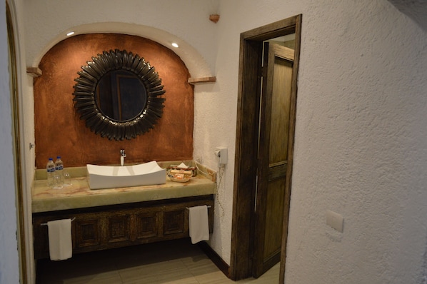 Un baño con lavamanos blanco, espejo y armarios de madera.