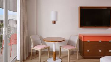 Una habitación de hotel con una mesa redonda de madera, dos sillas, un televisor y un aparador de madera.